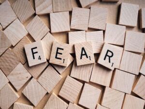 Brown Scrabble tiles letter side down except for the letters that spell FEAR