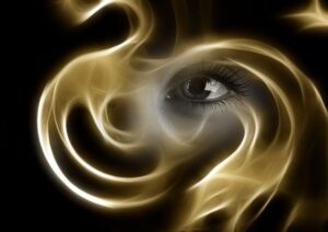 An eye is seen from behind a golden and white swirling light.