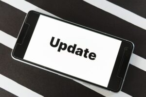Black and white stripe back ground with a cell phone on top - "Update" shows on the cell phone, white back ground, black letters.